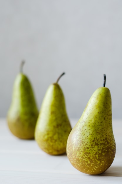 Trois poire verte dans une rangée sur une table en bois blanche