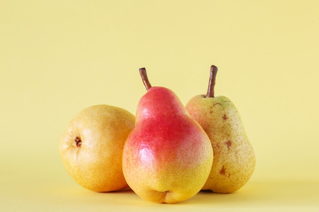 Trois poires mûres sur fond jaune.