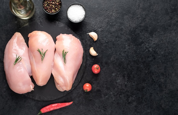 Photo trois poitrines de poulet crues sur fond de pierre avec espace de copie pour votre texte