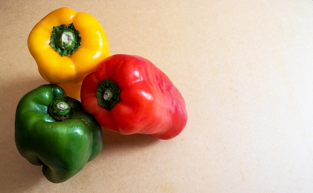 Trois poivrons de couleurs différentes appuyés les uns contre les autres