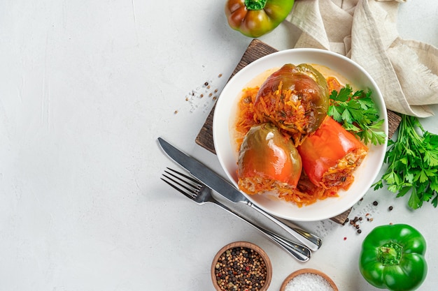 Trois poivrons farcis avec du riz à la viande et des légumes sur fond clair