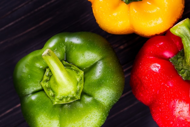 Trois poivrons sur un fond en bois, cuisson de salade de légumes