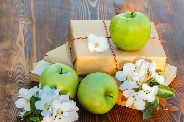 Trois pommes vertes et fleurs sur une saison de récolte de fond en bois