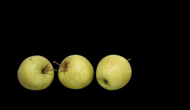 Trois pommes vertes mûres sur fond noir