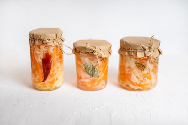 Trois pots de choucroute et de carottes dans son propre jus d'épices, table en bois blanc. plat fermenté traditionnel fait maison de Russie et d'Allemagne.