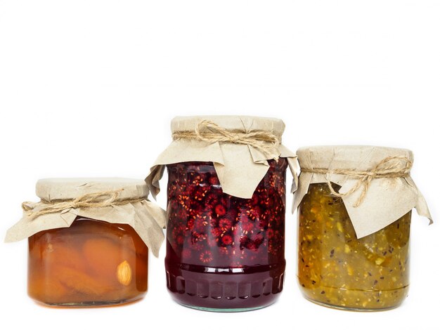 Trois pots de confiture différente sur une surface blanche