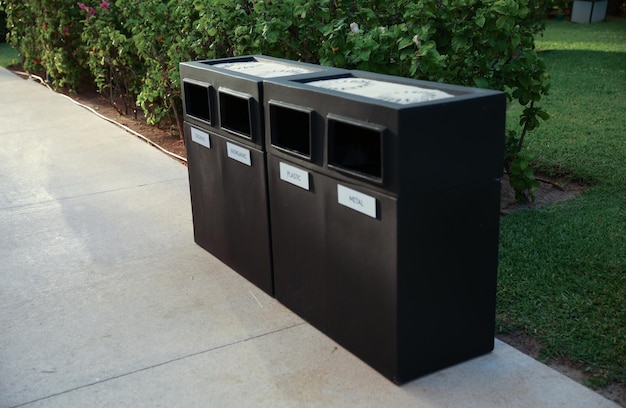 Trois poubelles sur un trottoir avec un panneau qui dit " élimination des déchets ".