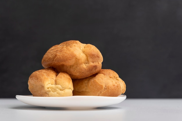 Trois profiteroles sur plaque blanche. Popovers et éclairs maison. Eclairs sans crème.