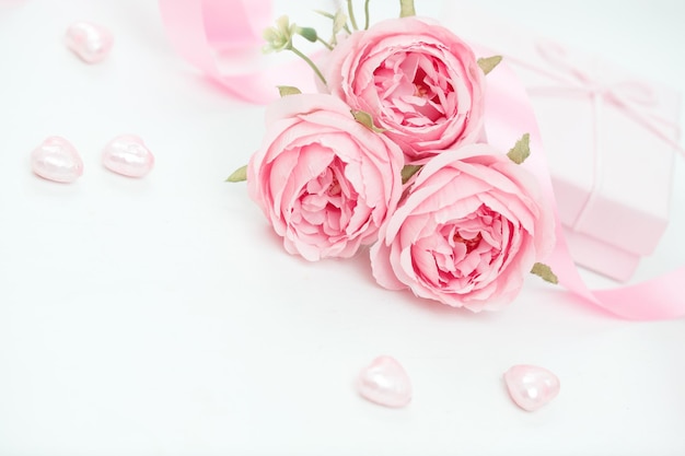 Trois roses roses avec ruban et boîte à cadeaux sur la table blanche Concept du jour de la Saint-Valentin