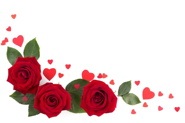 Photo trois roses rouges et de nombreux petits coeurs en papier isolés sur fond blanc, amour cadeau romantique pour la saint-valentin