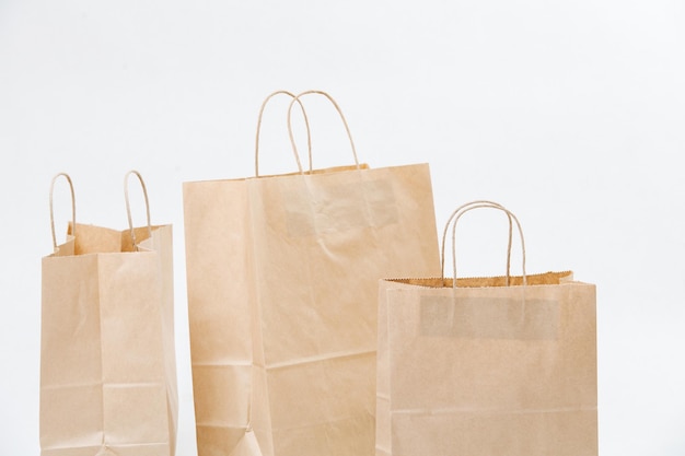 Trois sacs en papier brun vides disposés dans une composition sur fond blanc. Objets compostables écologiques.