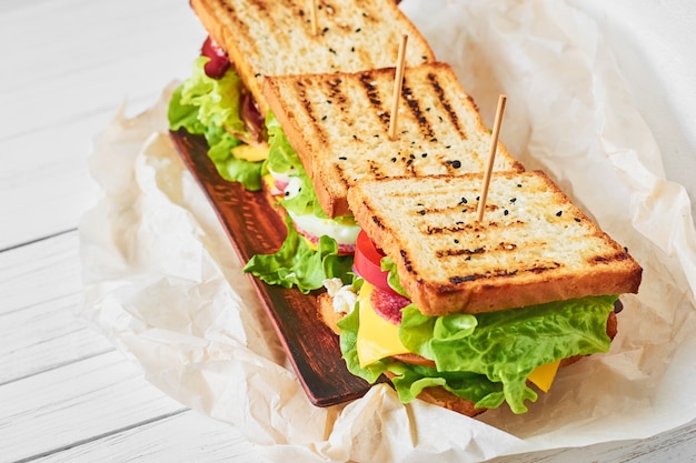 Trois sandwichs au jambon, laitue et légumes frais sur une assiette, gros plan