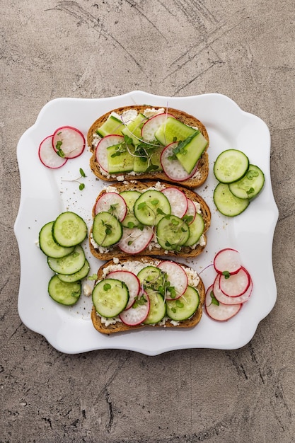 Trois sandwichs aux légumes et fromage végétal sur une assiette carrée blanche