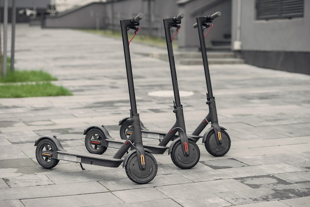 Trois scooter électrique noir élégant et moderne sont garés près du grand centre de bureaux