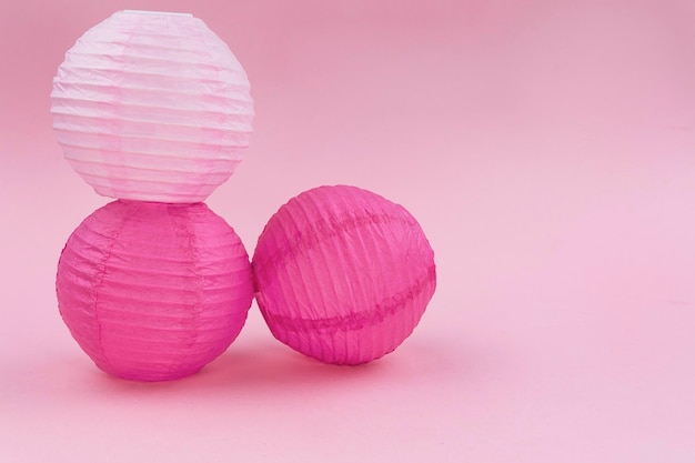 Trois sphères dans différentes nuances de papier sur fond rose