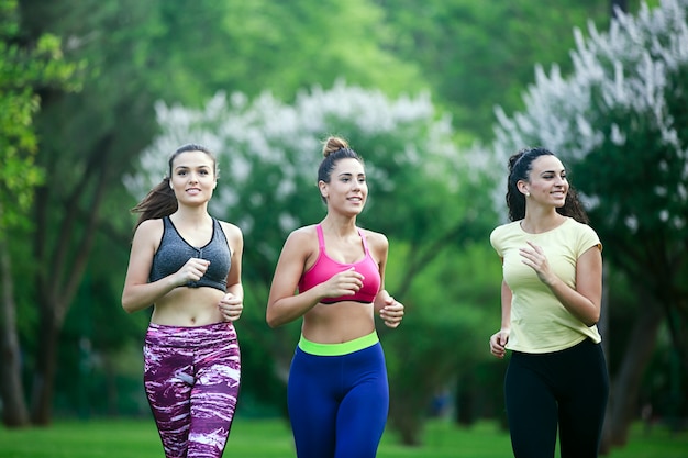 Trois sportives gaies courir dans le parc