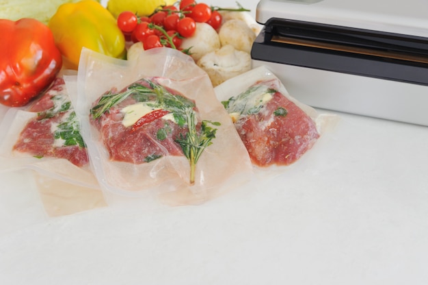 Trois steaks crus dans un emballage sous vide et un emballage sous vide. Cuisine sous-vide, nouvelle technologie.