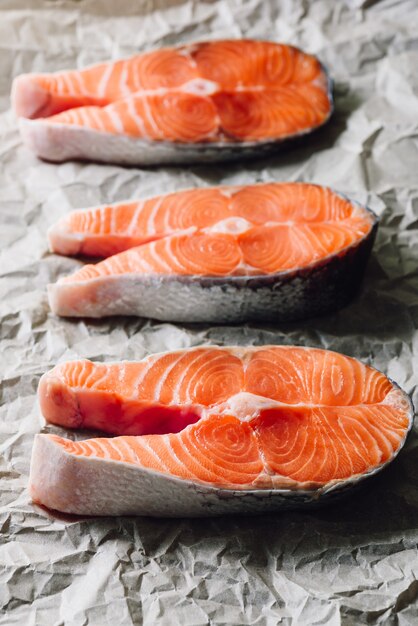 Trois steaks de saumon cru sur papier parchemin