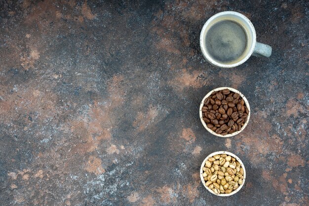 Trois tasses avec différentes étapes de café. Haricots verts et torréfiés, americano.