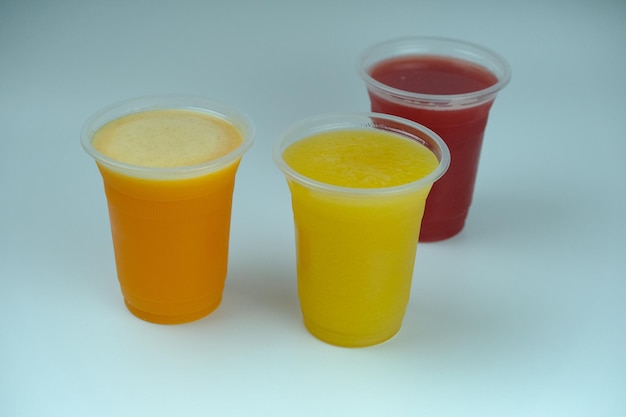 Trois tasses de jus de fruits avec un fond blanc