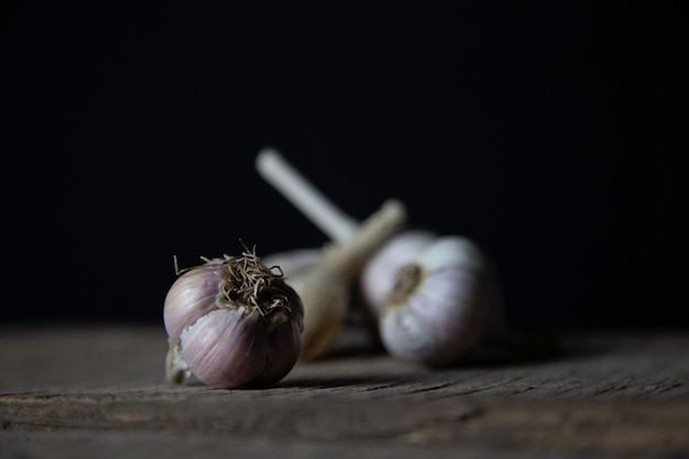 Photo trois têtes d'ail se trouvent sur la table tourné en discret sur un fond sombre