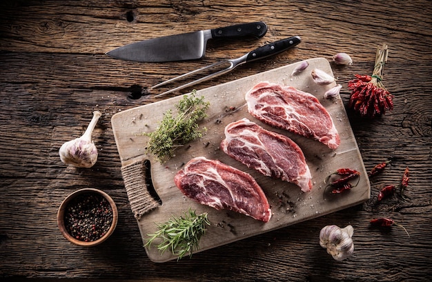 Photo trois tranches de cou de porc aux herbes, épices chili et ail sur une planche à découper