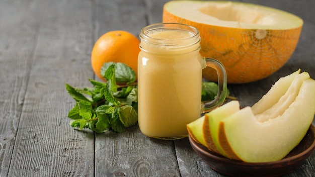 Trois tranches de melon et smoothies sur une table en bois.