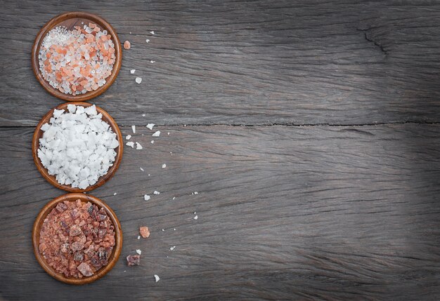 Photo trois types de sel dans des bols en bois sur un fond en bois