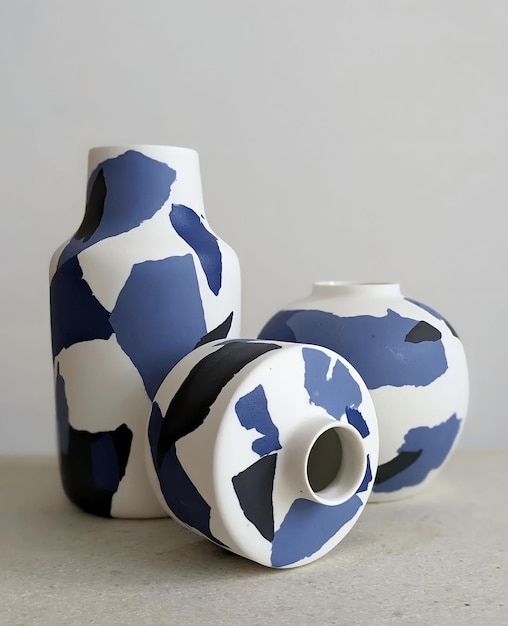 Trois vases en céramique aux motifs bleus et blancs sont posés sur une table.