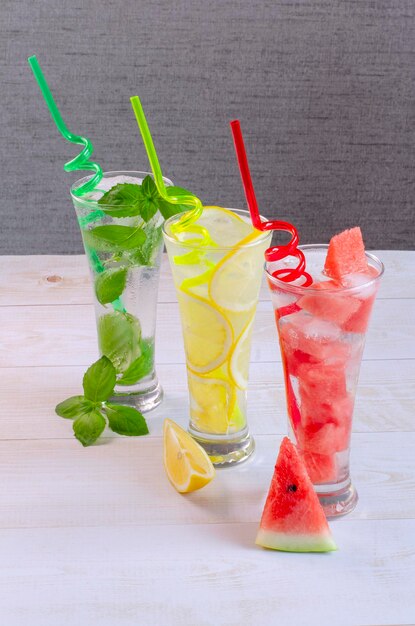 Trois verres avec diverses boissons non alcoolisées citron pastèque et menthe avec de la glace