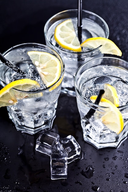 Trois verres avec de l&#39;eau gazeuse froide et fraîche avec des tranches de citron et des glaçons