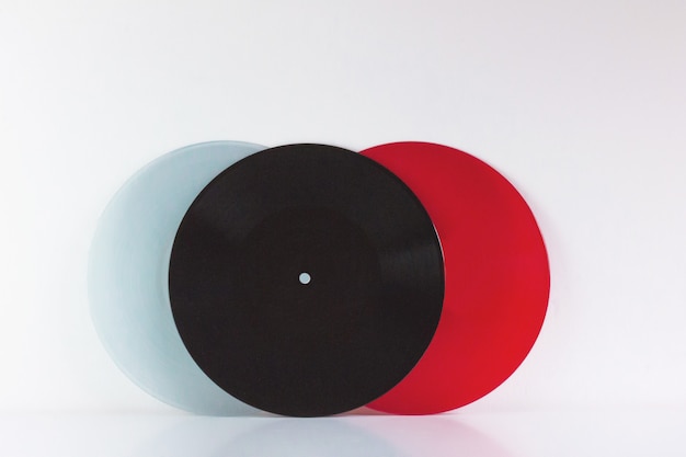 Photo trois vinyles, bleu, noir et rouge, sur blanc, avec espace