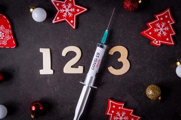 Photo la troisième dose de vaccin contre la covid et le concept du vaccin et les chiffres et les décorations de noël de la seringue sont visibles