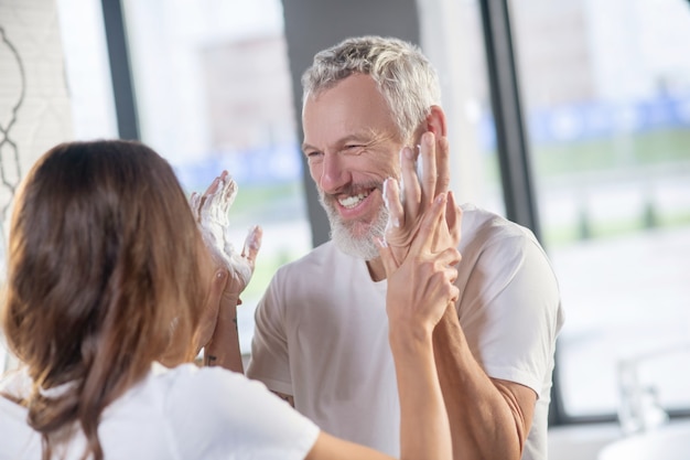 Tromper. Un homme et une femme jouant avec de la mousse à raser