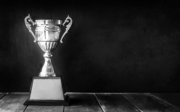 Trophée de champion noir et blanc sur une table en bois avec espace de copie au tableau