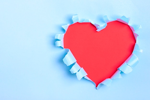 Trou En Forme De Coeur Rouge à Travers Du Papier Bleu