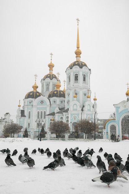 Un troupeau de colombes au premier plan Derrière l'Église orthodoxe dans la neige Concept architecture voyage religion