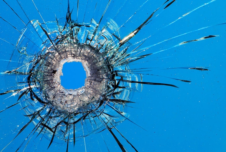 Photo trous de balle dans le verre sur le fond du ciel bleu