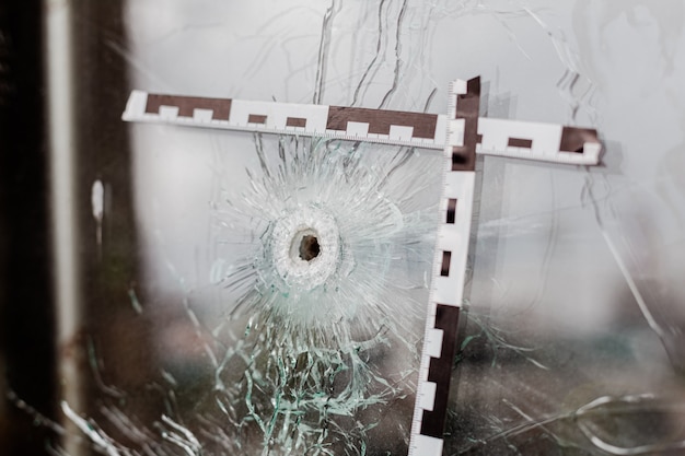 Trous de balle dans une vitrine en verre marquée d'un ruban de police