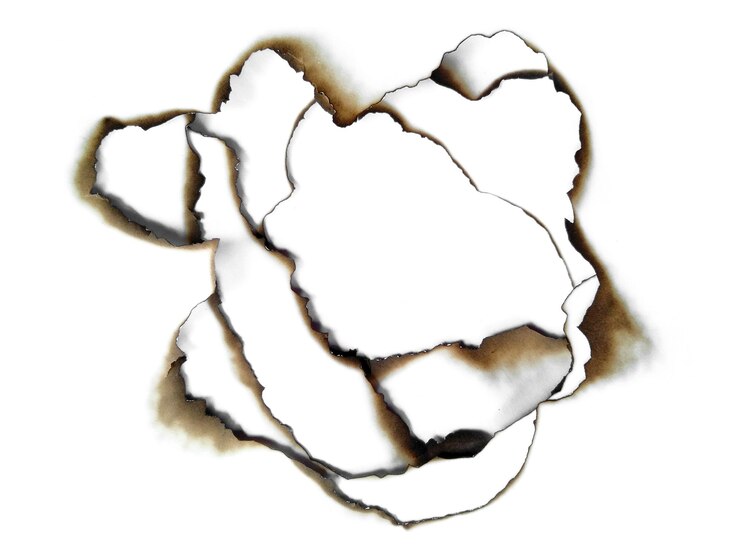 Photo trous brûlés dans un morceau de papier isolé sur fond blanc