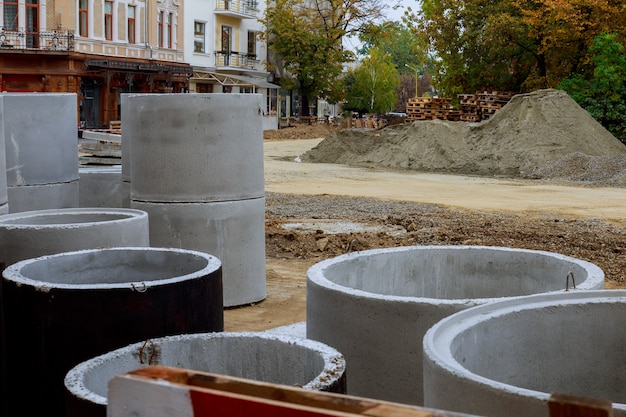 Les trous d'homme en béton de tuyaux sont stockés sur le sol, prêts pour la construction de l'installation