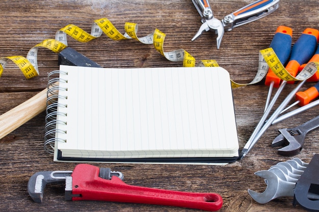 Trousse d'outils et cahier vierge sur des planches de parquet en bois