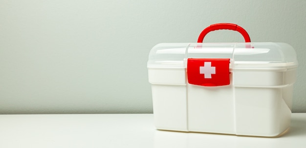 Trousse de premiers secours. Boîte blanche avec une croix et un fermoir rouge sur fond gris.