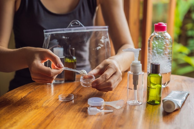 Trousse de voyage pour le transport de cosmétiques dans un avion Les cosmétiques sont prêts à être versés dans de petites bouteilles Une femme déplace les cosmétiques à emporter avec elle