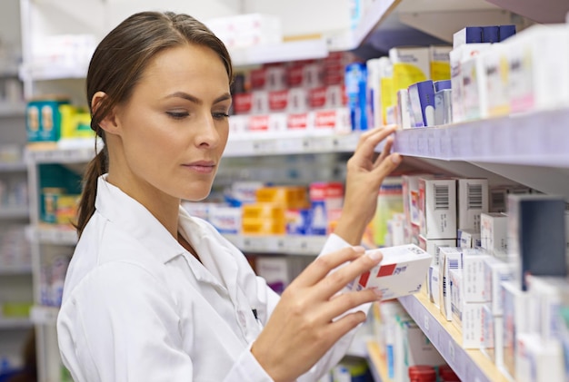 Trouver le bon médicament photo d'un jeune pharmacien attrayant vérifiant le stock dans une allée