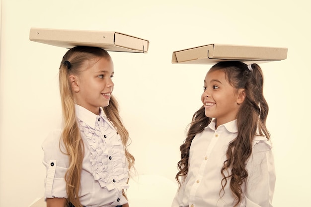 Trouver l'équilibre Des écolières avec une jolie coiffure en queue de cheval portent des dossiers sur la tête Des écolières parfaites avec des cheveux fantaisie bien rangés et une posture appropriée portent des dossiers sur la tête Équilibre et fardeau des connaissances