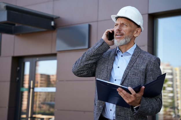 Trouver des solutions sérieuses matures architecte ingénieur manager portant un casque à l'écart de parler sur