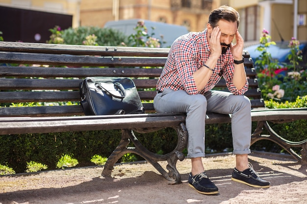 Trouver la sortie. Moody homme déprimé se sentir fatigué alors qu'il était assis sur le banc