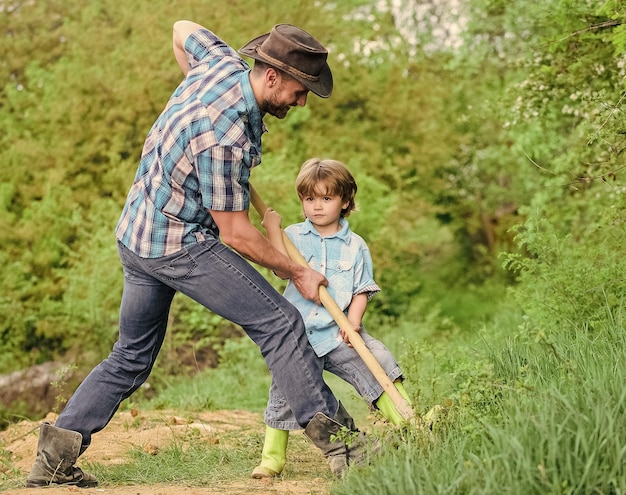 Trouver des trésors Petit garçon et père avec une pelle à la recherche de trésors Enfance heureuse Aventure chasse aux trésors Petit assistant dans le jardin Enfant mignon dans la nature s'amusant avec papa cow-boy