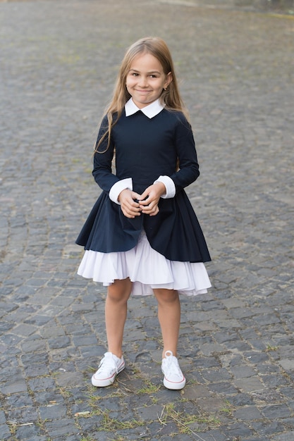 Trouvez votre diva intérieure. Un enfant heureux porte un uniforme à l'extérieur. Look mode de petite écolière. L'éducation formelle. Retour à la mode scolaire. Tendances scolaires. Journée du savoir. 1er septembre. La forme vous suit.